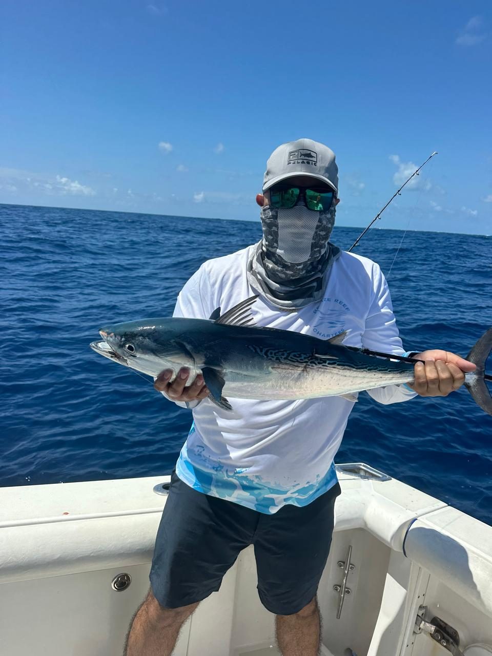 Angler in a sun buff holding a fresh catch on the deck