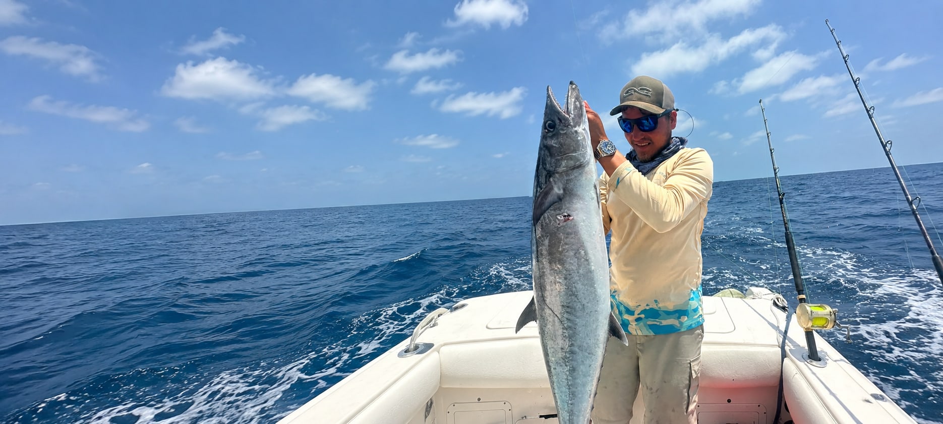 An angler holding a kingfish aboard a boat offshore of Belize