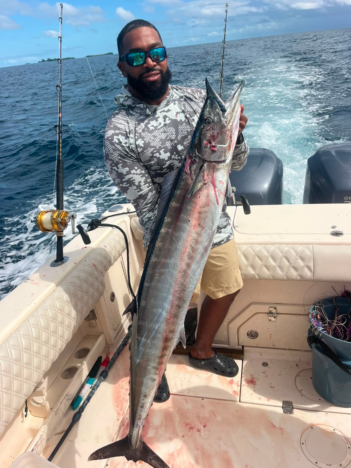 Angler holding a big wahoo on the deck of a centre console off Belize